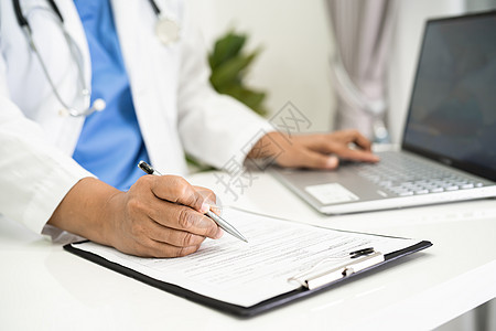 医生用医院的膝上型电脑在剪贴板上写医疗说明女士病人处方外套实验室治疗笔记本写作男人考试图片