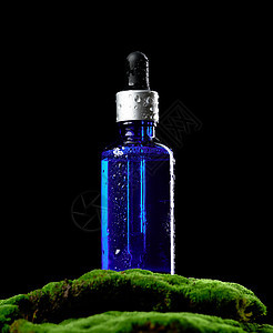 带吸管的蓝色玻璃瓶站在绿色苔藓上 黑色背景 化妆品 SPA 品牌模型图片