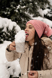 女人穿着温暖的冬衣 站在大圣诞树旁边露着户外 从杯子里舔雪市场店铺森林季节家庭幸福假期乐趣微笑成人图片