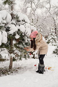 美丽的女人穿着温暖的冬天衣服 在雪天的一个公园里装饰圣诞树庆典装饰品微笑风格成人喜悦乐趣季节女性幸福图片