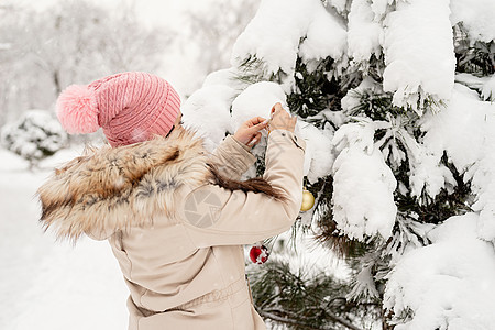 美丽的女人穿着温暖的冬天衣服 在雪天的一个公园里装饰圣诞树快乐微笑家庭季节成人庆典女士女性喜悦装饰品图片