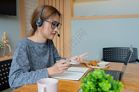 亚洲女性戴耳机看笔记本电脑享受与导师在线学习 听音频讲座观看网络研讨会准备考试 电子学习 自我教育概念教育大学课程班级学生女士工图片