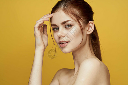 裸露的肩膀和清晰的皮肤黄色背景表情微笑外科塑料按摩化妆品女士治疗奶油美容嘴唇图片