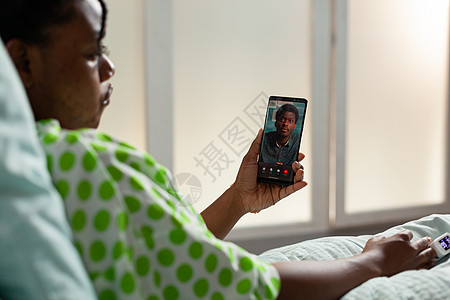 拥有智能电话的非洲美国青年病人解释疾病专门知识;说明病情专业知识图片
