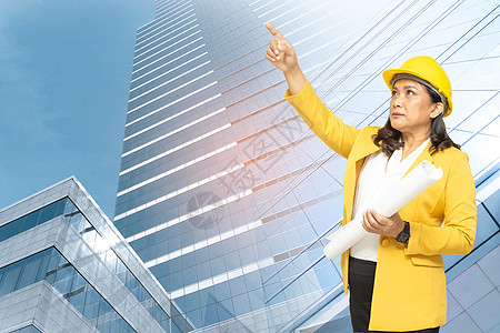 具有蓝图的亚洲工程师女性站在建筑背景中 具有复制空间 工程施工和建筑概念图片