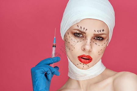 蓝手套注射针筒的女病人在脸上举起粉红色背景时 手部轮廓程序药品女性外科治疗女孩护理医院成人医生图片