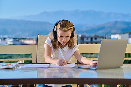 10至11岁女童在家中网上学习电子教育耳机会议学生青春期微笑家庭作业写作电话电脑图片