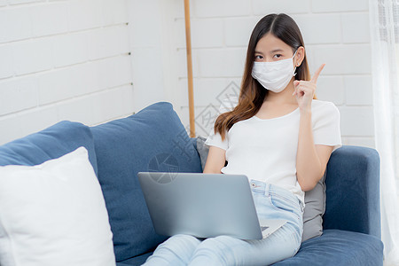 戴面罩的年轻亚洲女商务人士思考想法 在家里用笔记本电脑在线工作 在客厅上网 戴医用口罩的女孩和 covid19 隔离区 待在家里图片