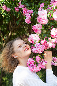 玫瑰花女人粉彩粉色玫瑰花的迷人女孩 夏季时间 美丽的年轻女子手捧盛开的月季花 遍地开花 粉红色的玫瑰花背景