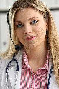 快乐笑笑的年轻医生在耳机上的肖像专家关心中心工作微笑诊所临床考试女性药品图片