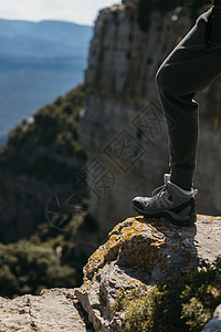 一个女人在阳光明媚的一天踩着一块 背面深厚的小石头上爬鞋 复制空间图片