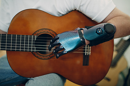 年轻残疾人在店里用人工假肢手 在吉他上弹琴图片