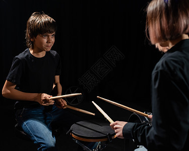 年轻的天主教女青年教男孩用黑人背景在工作室里打鼓 音乐学校学生 请讲班级女士教育音乐会笔记教学音乐家作曲家歌曲天赋图片