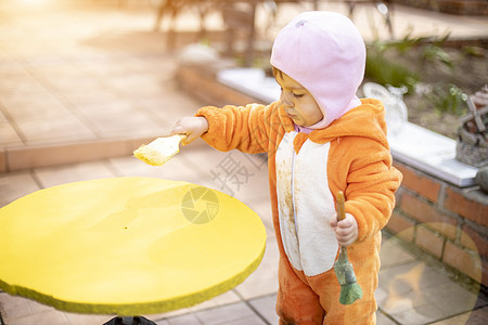 可爱的小小孩涂画黄色圆桌和刷子教育阳光幼儿园桌子女孩童年艺术乐趣太阳画笔图片