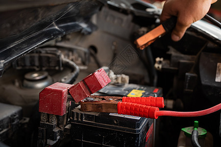 机械师把夹子连接到放出的汽车电池上金属助推器发动机活力技术柴油机工具机器维修电缆图片