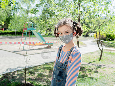 在科罗纳病毒流行期间 一个戴着医疗面具的小女孩不得在操场玩耍 10图片