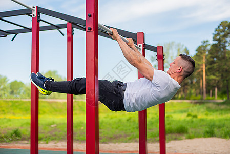 白种男人在不平坦的酒吧做背木板 在运动场上锻炼平行竞赛运动员活力腹部训练手臂运动力量体操图片