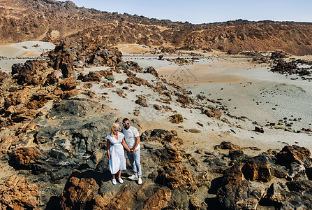 一个穿着白色衣服和眼镜的男人和一个女孩站在泰德火山的火山口 一对夫妇站在西班牙特内里费岛火山口的一座山上世界公园慢跑者沙漠石头假图片