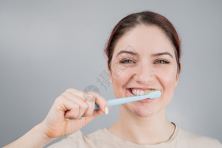 白种女人刷牙的特写肖像 女孩执行早晨口腔卫生程序清洁度浴室牙刷牙膏卫生保健药品快乐程序化妆品图片