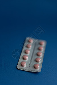 医学和药丸 经典蓝色背景特写上的多色药物 蓝色背景上有粉红色药丸的盘子 从倒置的罐子中溢出到蓝色表面的多色药丸药片治疗剂量健康化图片