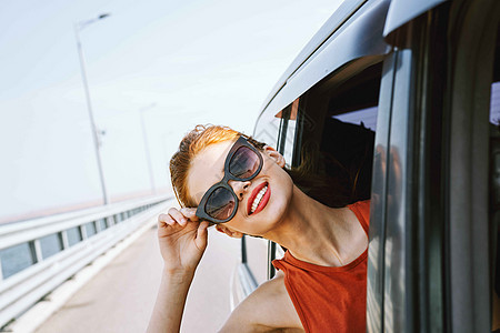 身戴墨镜的妇女在汽车窗外看望着的车窗 旅行生活方式太阳镜夫妻游客车辆蓝色乐趣晴天自由潮人假期图片