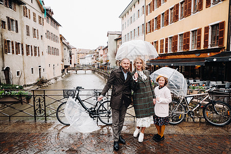 在法国安妮西的雨天下 有雨伞的美丽家庭 家庭在雨中行走旅行景点天空寂寞下雨天女士爸爸好心情妈妈孩子图片