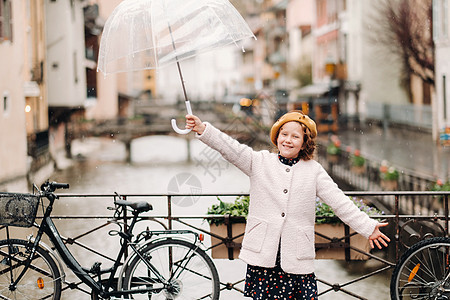 在法国安妮西 穿着透明伞的漂亮大衣的女孩 开心地在雨中举起伞来 她高兴得要命女士假期好心情男人寂寞情绪城市下雨天地标小姑娘图片