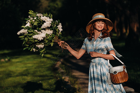一个长头发 草帽和夏裙的漂亮女孩的肖像 花园里有花束花朵连衣裙发型裙子太阳裙香味蓝色女士头发公园紫色图片