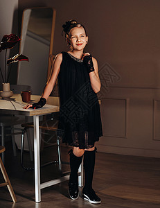 一个穿黑衣服的时装小女孩 在桌子附近的内地 站着窗户黑色教育乡愁风格发型头发孩子们复古裙子图片