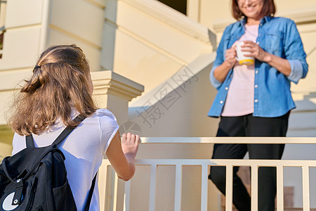 带着背包的女学生 在房子门廊上和她母亲在一起父母书包家庭学生女性妈妈女孩女儿教育瞳孔图片