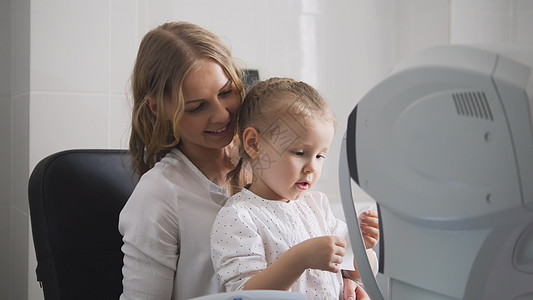 验光师检查孩子的视力-眼科医生室的母亲和孩子图片