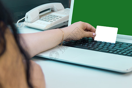 女性在支付网上绿屏购买费时持有银行卡 请查看InfoFinland上的图片