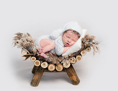 新生婴儿肚子上睡着 在婴儿床上卷起来毛皮木头孩子男性帽子休息女孩婴儿床幸福童年图片