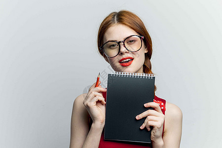 带着眼镜的开心女人 红裙子笔记工作职业情绪头发笔记本技术成功办公室经理相机名片图片