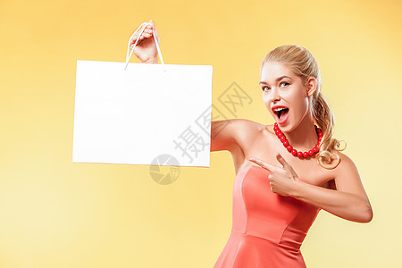 售卖 年轻微笑的年轻女子在黑色星期五假日展示购物袋 有复制空间的黄色背景女孩图片