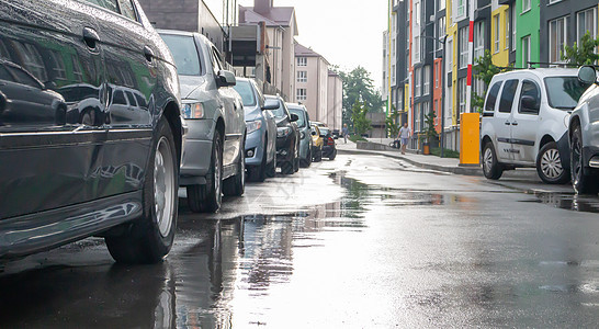 在雨天没有人停着车的城市街道 路上下雨 雨和车 多雨的城市街道上停放汽车的背景 对称停放的汽车前灯沥青运输雨滴气候水坑车辆危险城图片