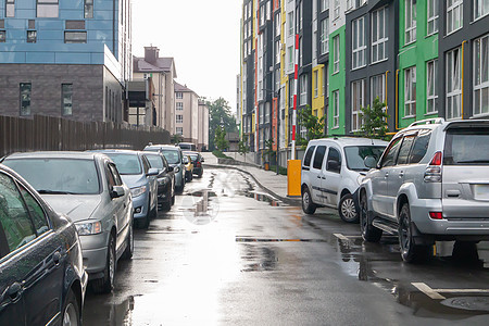 在雨天没有人停着车的城市街道 路上下雨 雨和车 多雨的城市街道上停放汽车的背景 对称停放的汽车雨滴城市天气季节阴雨湿度速度运动前图片