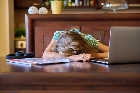 睡在家里的桌子上睡觉的疲倦女学生图片
