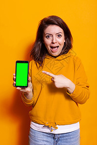 指向智能手机垂直绿色屏幕的年轻女性图片