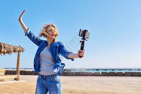 中年妇女录制关于智能手机 海上度假 自然 海景背景的视频照片闲暇游客海滩技术互联网女士博客太阳溪流图片