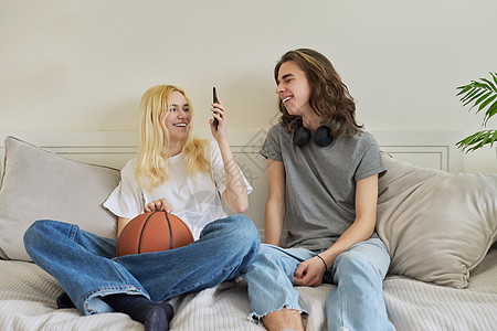 快乐笑笑嬉笑的少年男女使用智能手机玩得开心愉快青少年夫妻潮人朋友们男生细胞电话微笑学生技术图片