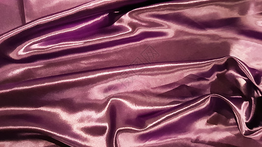 紫色织物特写背景 光滑优雅的丝绸或缎子质地可以用作背景 抽象布织物 织物背景编织装饰床单天鹅绒布料曲线波纹材料折叠涟漪柔软度背景图片