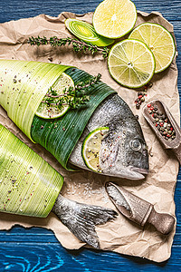 两条新鲜的生多拉多鱼 用棕榈叶包裹 撒上辣椒和大 gimolais 盐的混合物 还有酸橙和柠檬片 准备烘烤 为两人烹饪晚餐概念饮图片