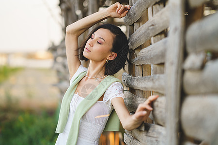 身着白裙子和绿水衣的亚洲妇女 在烟雾干燥棚附近摆姿势女性冒充国家绿色裙子乡村场地女孩烘干机农村图片