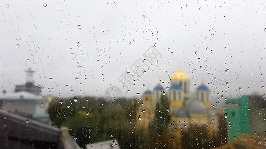 在多云的天气里 秋天的城市背景上滴着湿窗户 雨中窗外景色 雨中玻璃窗上的水滴 城市场景背景模糊液体下雨季节景观天空房子秋雨建筑物图片