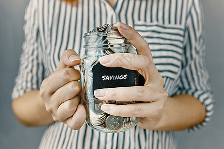 女人手里拿着硬币的玻璃瓶经济瓶子金融收益银行业会计女士积累存钱罐金属图片