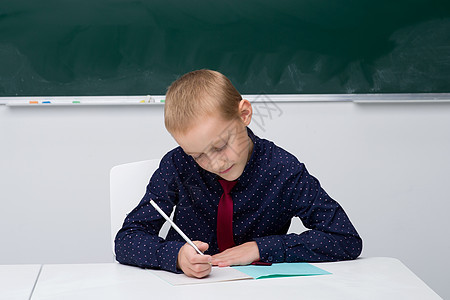 学校男孩在一张书桌旁的笔记本上写着幼儿园孩子班级智力知识童年快乐学习黑板瞳孔图片