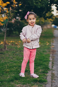 穿着粉红色夹克和粉红色短腿的小女孩 在公园里头发幸福微笑衣服公主喜悦裙子童年婴儿乐趣图片