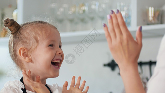 快乐的小女孩与母亲 在厨房拍掌 他们双手在厨房图片