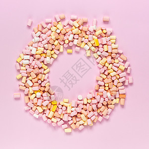 多色棉花糖的顶部视图 呈圆形框架形状 中心有一个文本区域 位于单色粉红色背景上图片